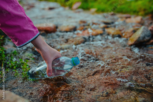 Woman fills clean spring water into a plastic bottle