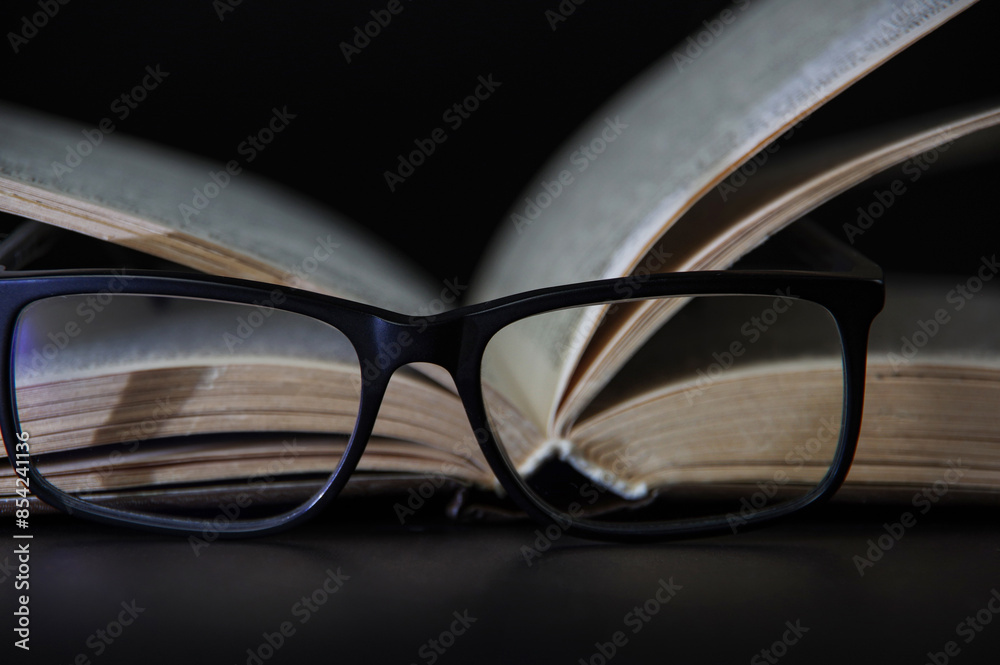 Open old book through reading glasses . Concept of knowledge, education and wisdom Open old book through reading glasses . Concept of knowledge, education and wisdom