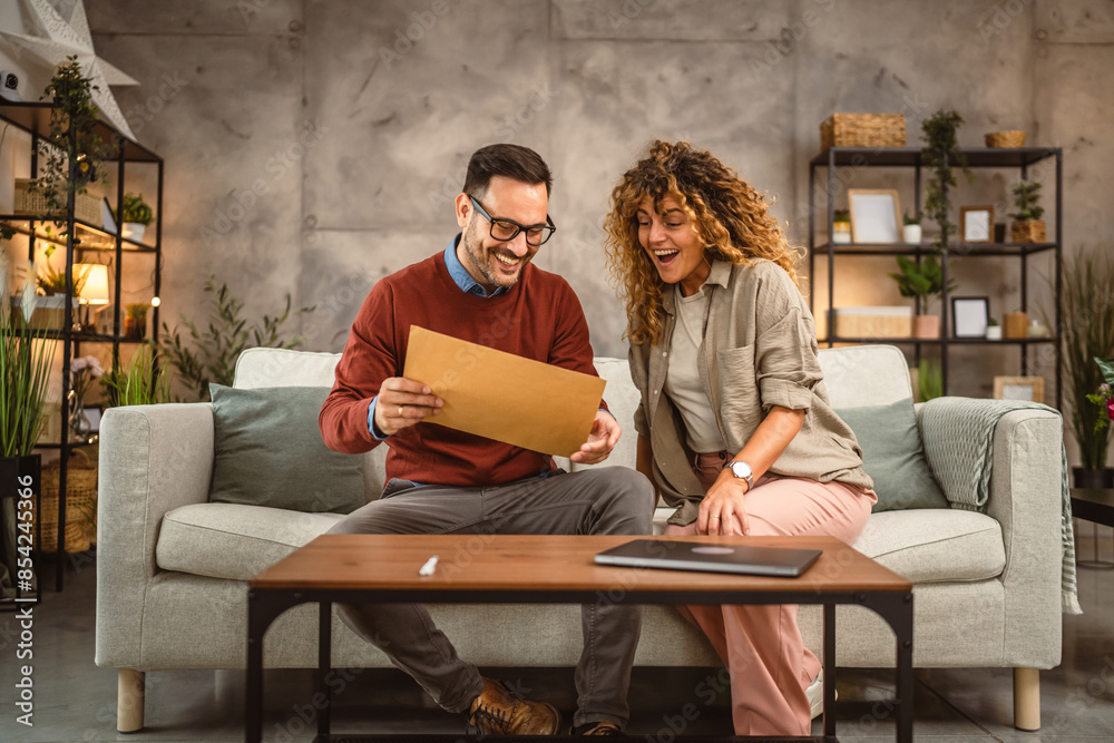 Happy excited couple open post letter envelope Happy excited couple open post letter envelope