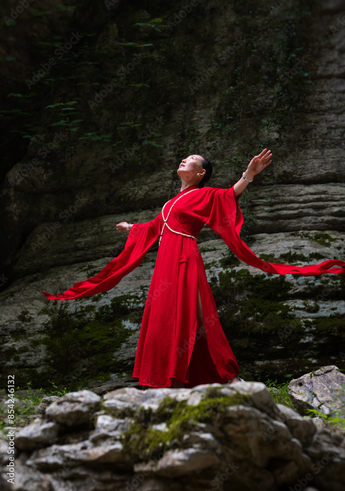 Asian girl in a beautiful red kimono in the middle of nature in a canyon