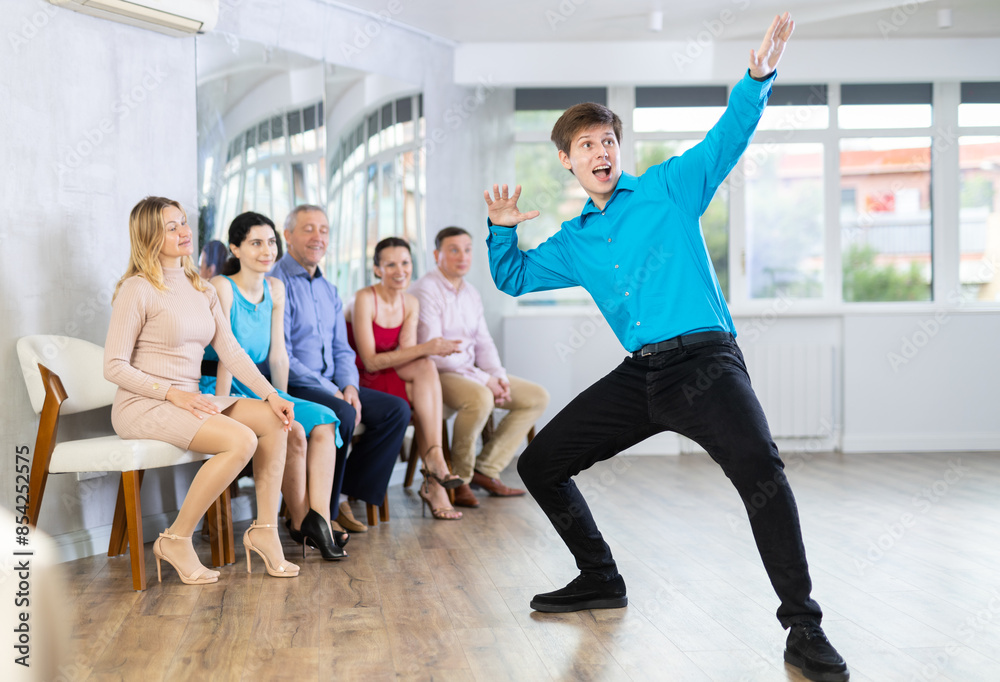 Obraz premium Young guy shows various dance hip hop moves at a dance lesson in the studio