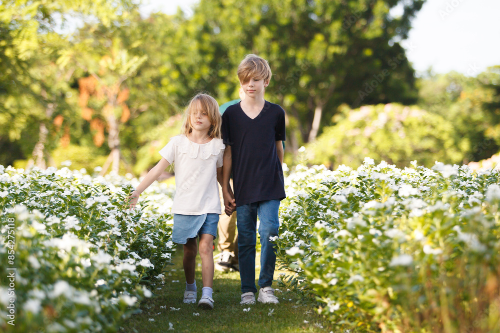 Fototapeta premium Caucasian white siblings playing at the park in morning.