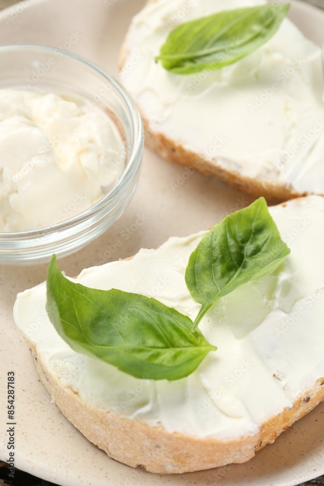 Delicious sandwiches with cream cheese and basil leaves on wooden table Delicious sandwiches with cream cheese and basil leaves on wooden table