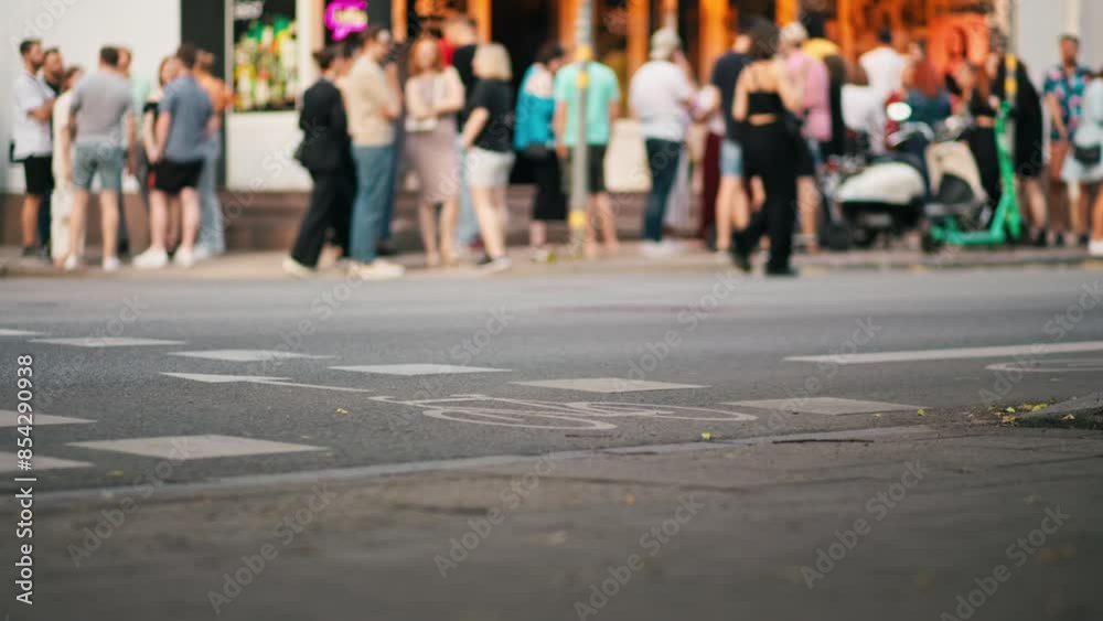 A vibrant crowd moves slowly outside a city cafe at night, bustling with socializing and lively interaction A vibrant crowd moves slowly outside a city cafe at night, bustling with socializing and lively interaction