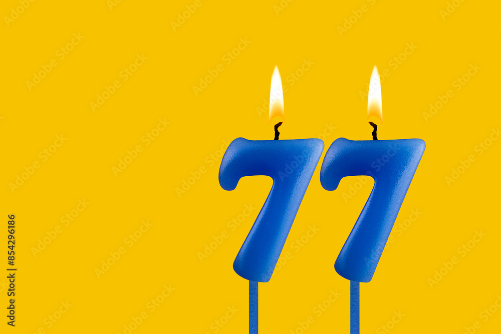 Blue candle number 77 - Birthday on yellow background Blue candle number 77 - Birthday on yellow background
