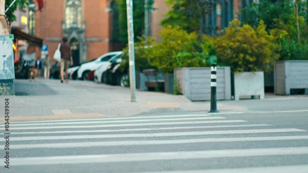 The peaceful sight of individuals moving slowly across a city road in daytime, capturing the urban flow