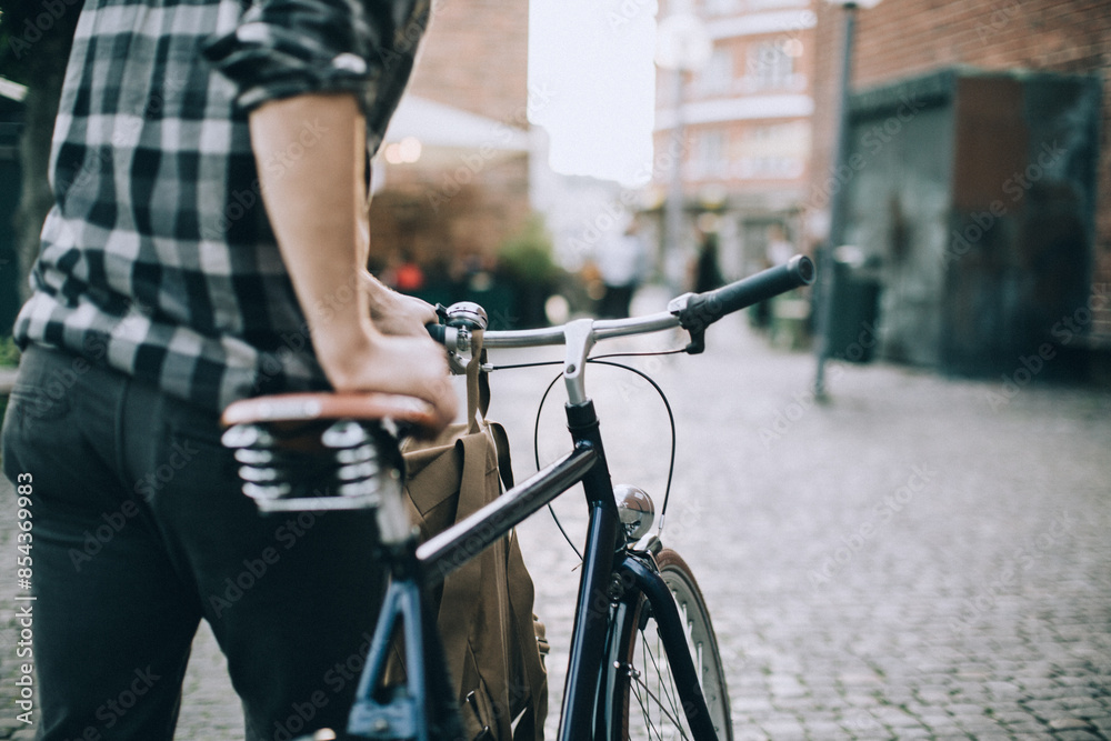 Fototapeta premium Young man pushing a bike through the city