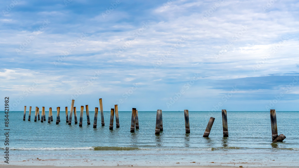 Beautiful view of leaning pillars of the old pier. Slanted concrete pole beach. Abandoned fishing pier pillar by the sea. Many of old concrete pillars were left on beach by the sea. Selective focus.