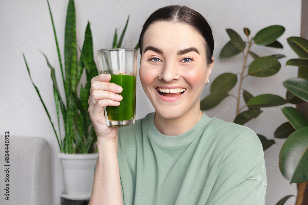Woman smiling and drinks green wheatgrass drink. Healthy lifestyle concept, green healthy vegetables Woman smiling and drinks green wheatgrass drink. Healthy lifestyle concept, green healthy vegetables