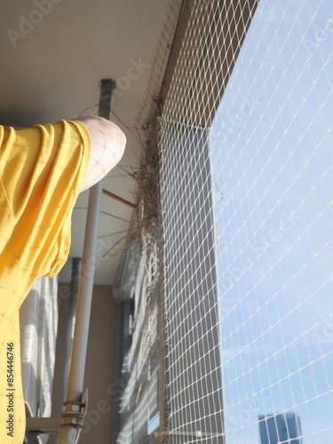 Cleaning dried hay of bird nest at the balcony of the condominium or apartment. Plastic net prevent and protect bird invader.