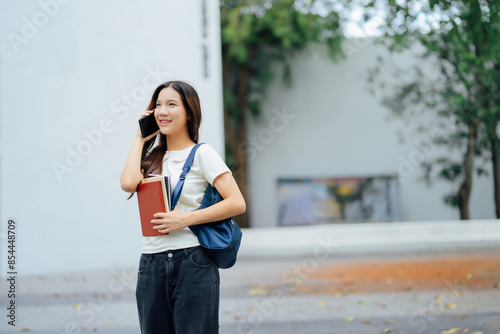 Happy Student Talking on Phone and Holding Books Outdoors on Campus