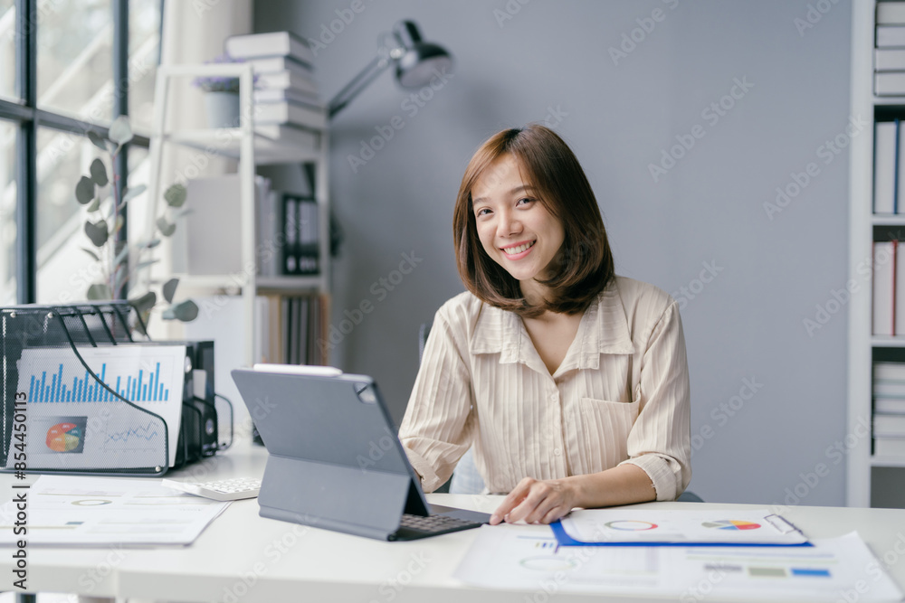 Young Professional Woman Working on Tablet in Modern Office with Documents and Charts Young Professional Woman Working on Tablet in Modern Office with Documents and Charts