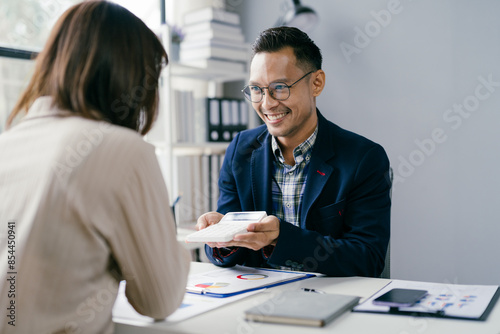 Business Meeting with Smiling Professional Handing Document Across Desk in Modern Office Setting