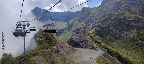 Breathtaking mountain view with cable cars traversing cloudcovered peaks and lush green trails