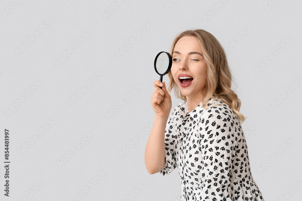 Young woman with magnifier on light background Young woman with magnifier on light background