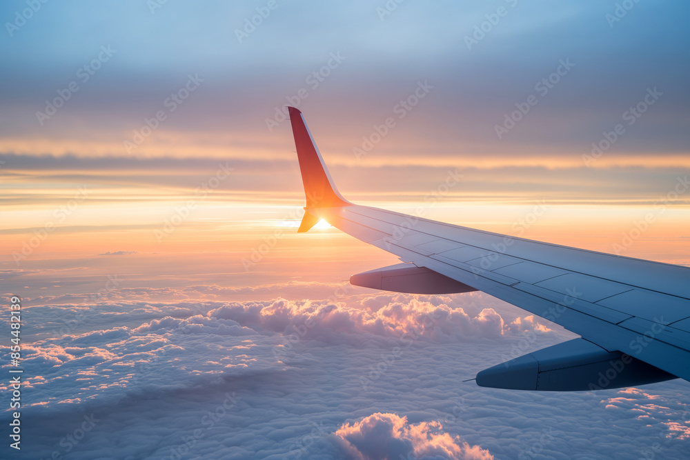 A breathtaking view of the sunset seen from an airplane window, with the aircraft's wing stretching over a sea of clouds tinted with the warm colors of the setting sun. A breathtaking view of the sunset seen from an airplane window, with the aircraft's wing stretching over a sea of clouds tinted with the warm colors of the setting sun.
