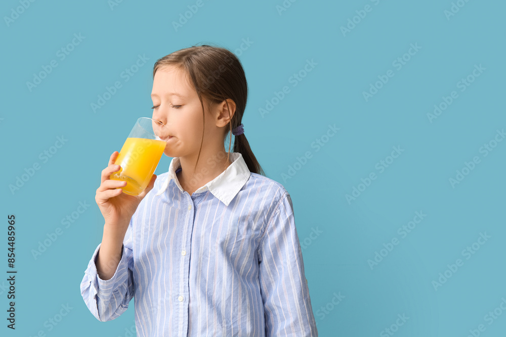 Little girl drinking orange juice on blue background Little girl drinking orange juice on blue background