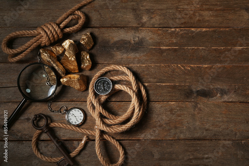 Travel equipment, key and golden nuggets on brown wooden background