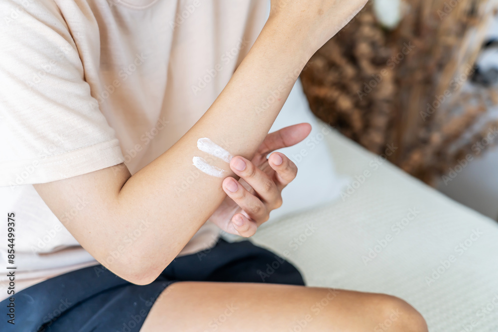 Young asian woman applying arm cream, lotion. Young Female do daily beauty body procedures or treatment. Hygiene and skin care concept, white cream rubbing to treatment skin condition, scrubbing