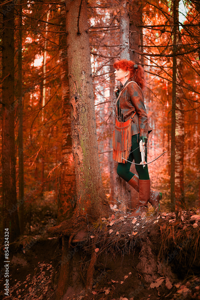 Mature model portraying a royal huntress with red curve hair is hunting with a crossbow in the in vibrant autumn forest in a thematic photo shoot Mature model portraying a royal huntress with red curve hair is hunting with a crossbow in the in vibrant autumn forest in a thematic photo shoot