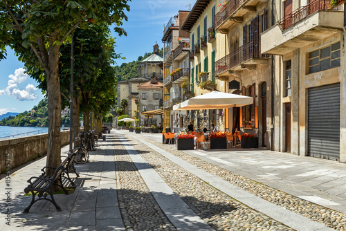 Tableau sur toile Narrow cobblestone street and along outdoor restaurants in old town of Cannobio, Italy