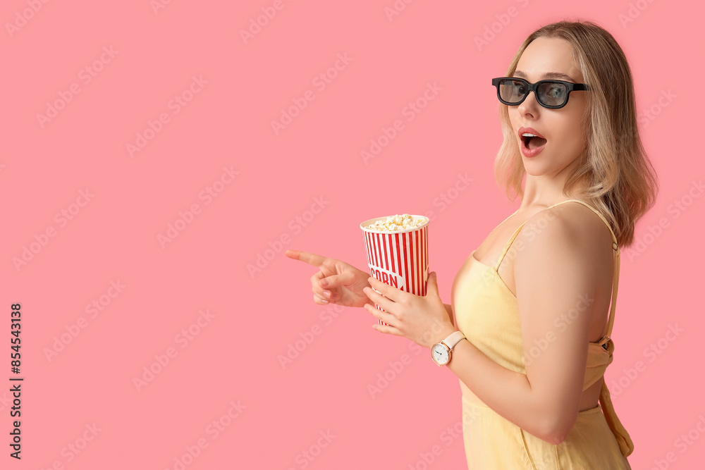 Emotional young woman in 3D glasses with bucket of popcorn on pink background Emotional young woman in 3D glasses with bucket of popcorn on pink background