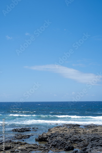 Views from the avenue of the village of La Santa. Sea coast. Blue water ocean in the background. Rocky beach. Clear sky. Lanzarote, Canary Islands, Spain