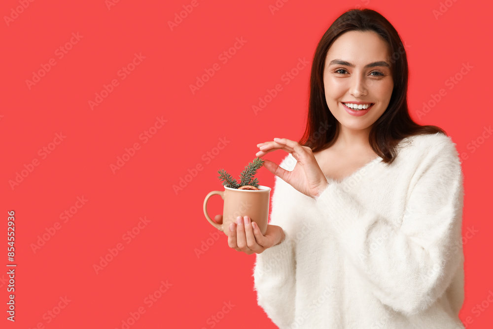 Happy young woman with cup of hot mulled wine on red background Happy young woman with cup of hot mulled wine on red background