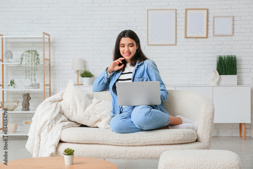 Young woman with laptop having online date on sofa at home Young woman with laptop having online date on sofa at home