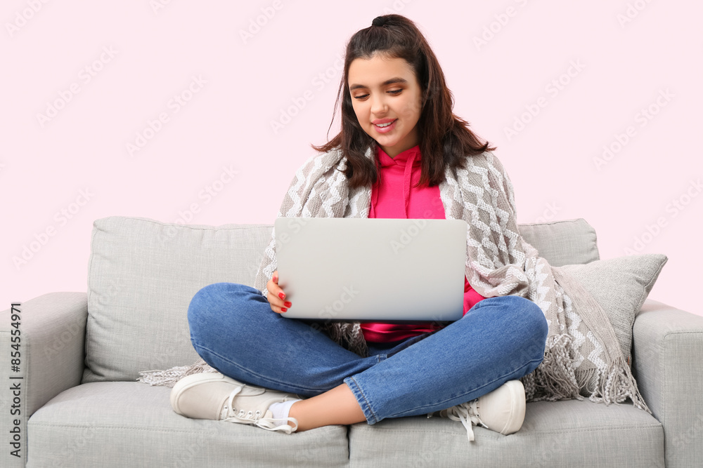 Young woman with laptop video chatting on sofa against pink background. Online dating concept Young woman with laptop video chatting on sofa against pink background. Online dating concept