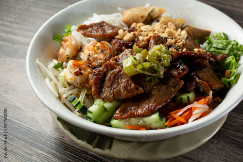 A closeup view of a bowl of Vietnamese bun, featuring grilled pork and shrimp.