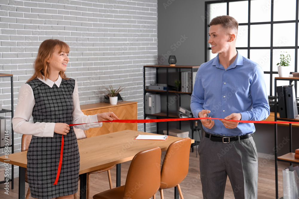 Fototapeta premium Business man cutting red ribbon at open ceremony in office