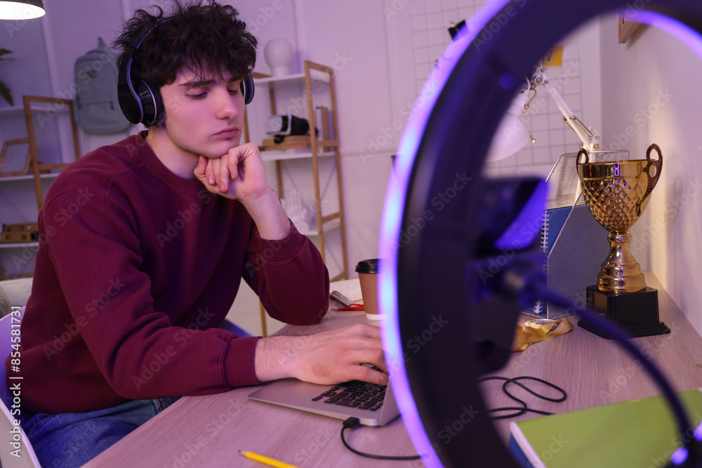 Fototapeta premium Male student studying while streaming at home in evening