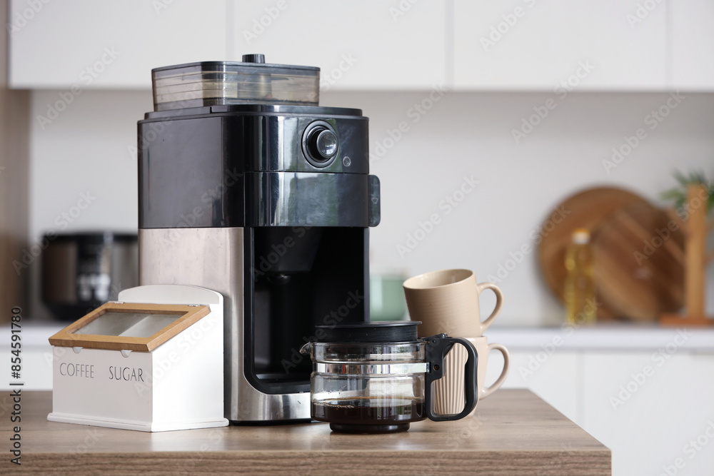 Modern coffee machine with cups, sugar and jar of beans on table in kitchen Modern coffee machine with cups, sugar and jar of beans on table in kitchen
