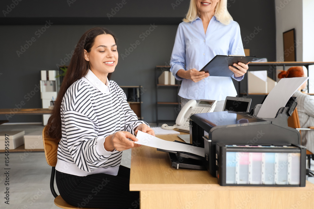 © Pixel-Shot - Young businesswoman with her colleague printing document at table in office