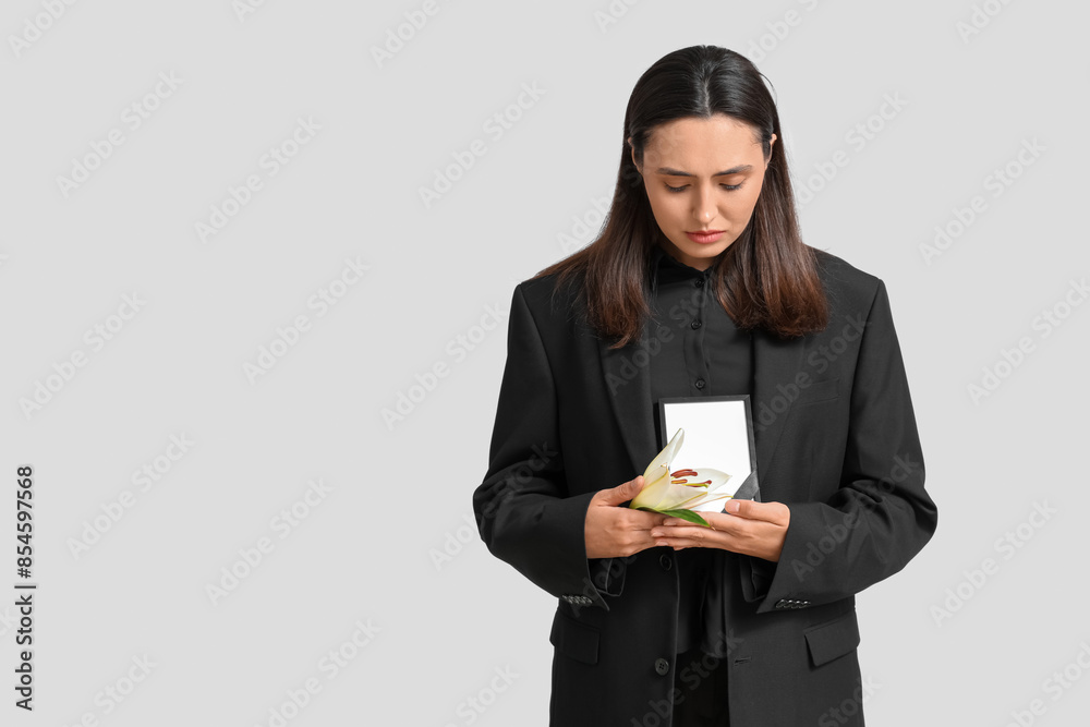 Young woman with funeral lily flower and photo frame on white background Young woman with funeral lily flower and photo frame on white background