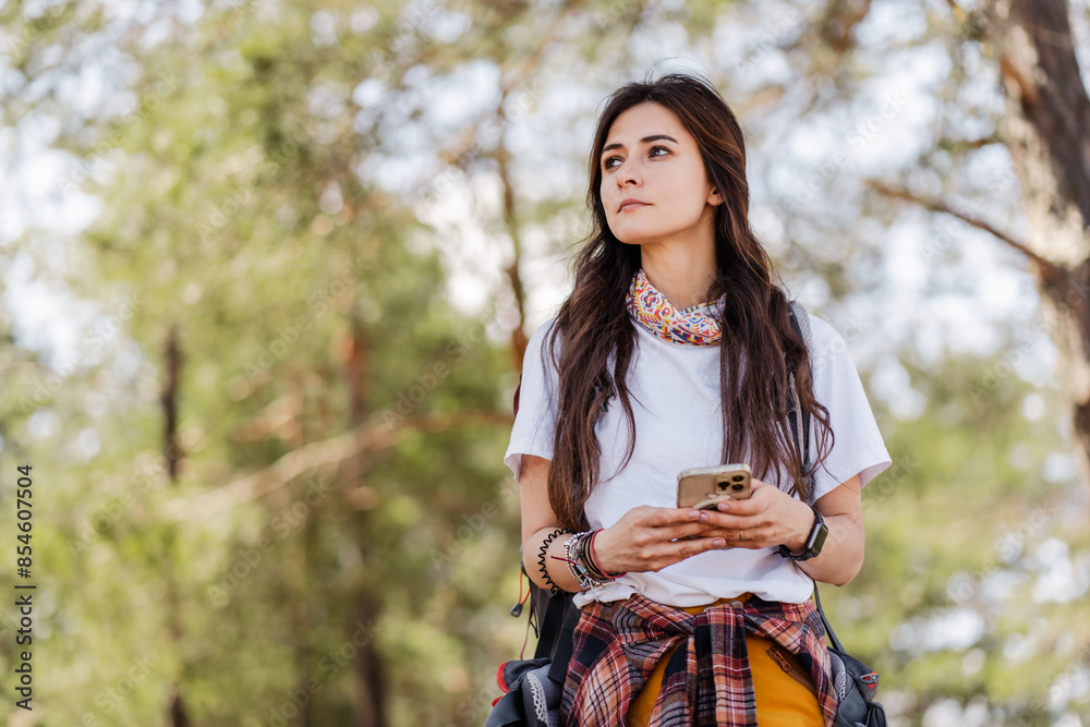 Focused girl tourist walking in forest and using smartphone gps
