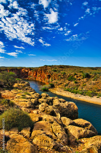 The canyon of the Yardie Creek in Cape Range National Park, Western Australia, with red and yellow limestone rocks and stunted outback vegetation
