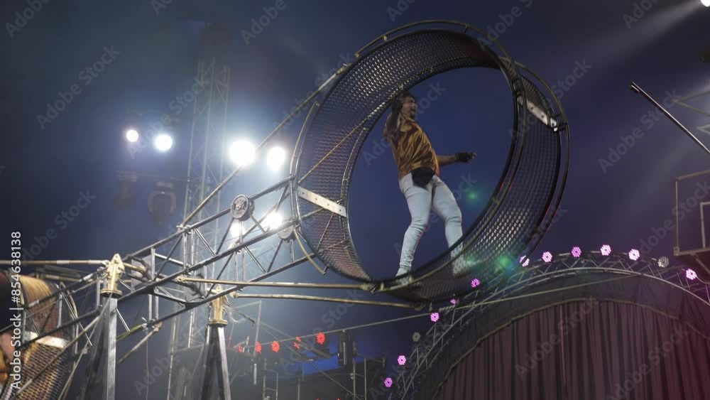 Two male acrobats in a rotating wheel of death perform under the dome ...