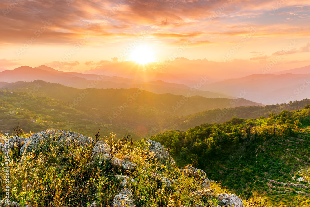 Obraz premium highland mountain landscape of beautiful sunset or sunrise with nice mountain peaks and slopes, green and golden hills and majestic cloudy sky on background