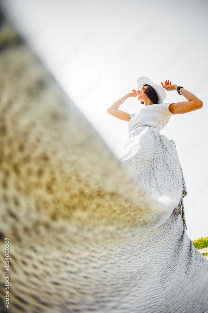 Naklejka premium young girl in a flowing white dress. girl in a white flowing dress, rear view, silk fabric fluttering in the wind.
