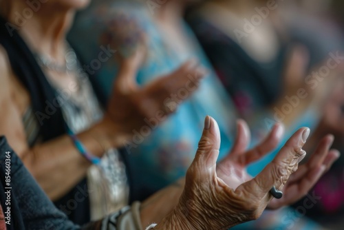 A close-up photo of senior womens hands in a yoga class, practicing a meditative gesture © Elmira