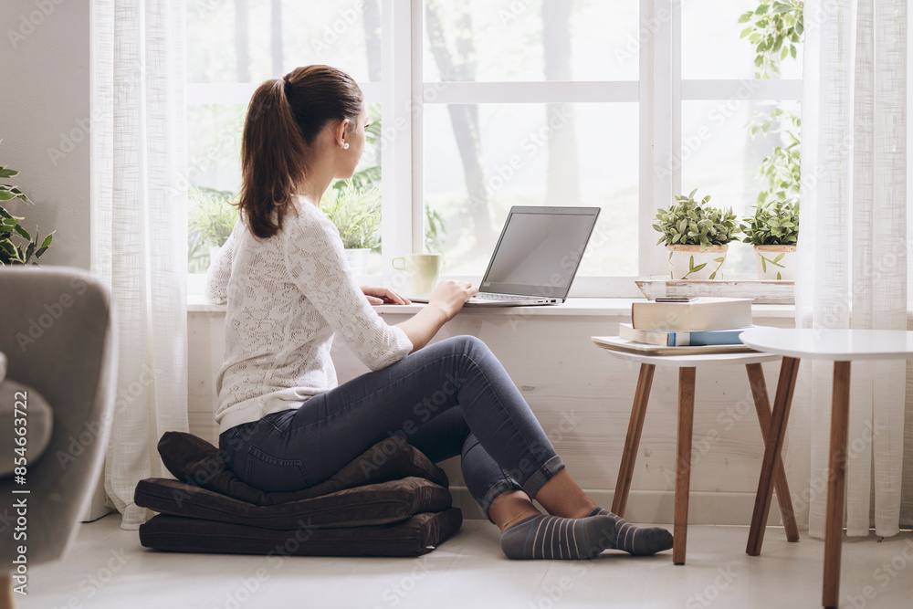 Young woman networking with her laptop at home Young woman networking with her laptop at home