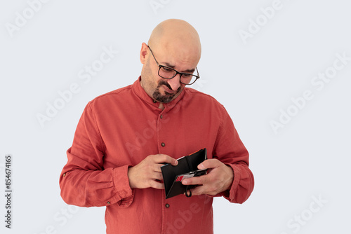 A man with a disgusted expression looking into his empty wallet. Perfect for themes of financial hardship, disappointment, and economic struggles