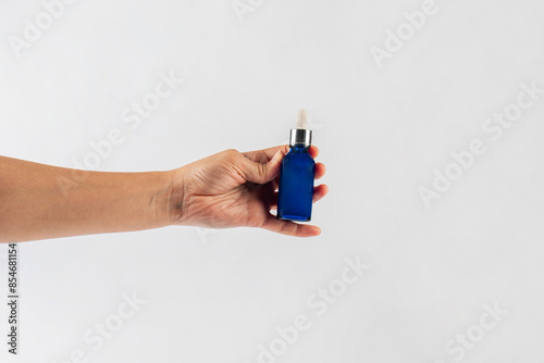 Wallpaper Mural Blue glass cosmetic bottle in hand, Skin care or sunscreen cosmetic on white background. Torontodigital.ca
