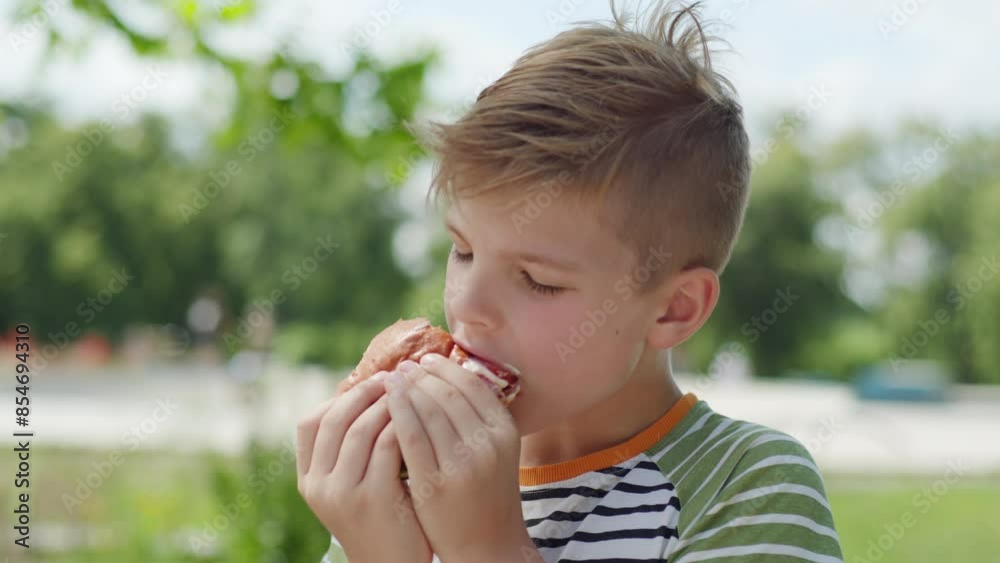 In a lively urban park, an 8-year-old kid enjoys a delicious burger, capturing the joy of outdoor eating in a bustling city environment In a lively urban park, an 8-year-old kid enjoys a delicious burger, capturing the joy of outdoor eating in a bustling city environment