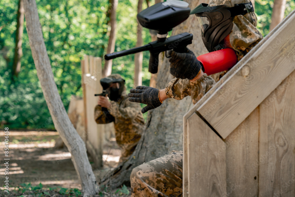 Obraz premium in the wild near tree structures player in a pintball uniform holds a pistol with a balloon team game camouflage clothing communication using hands