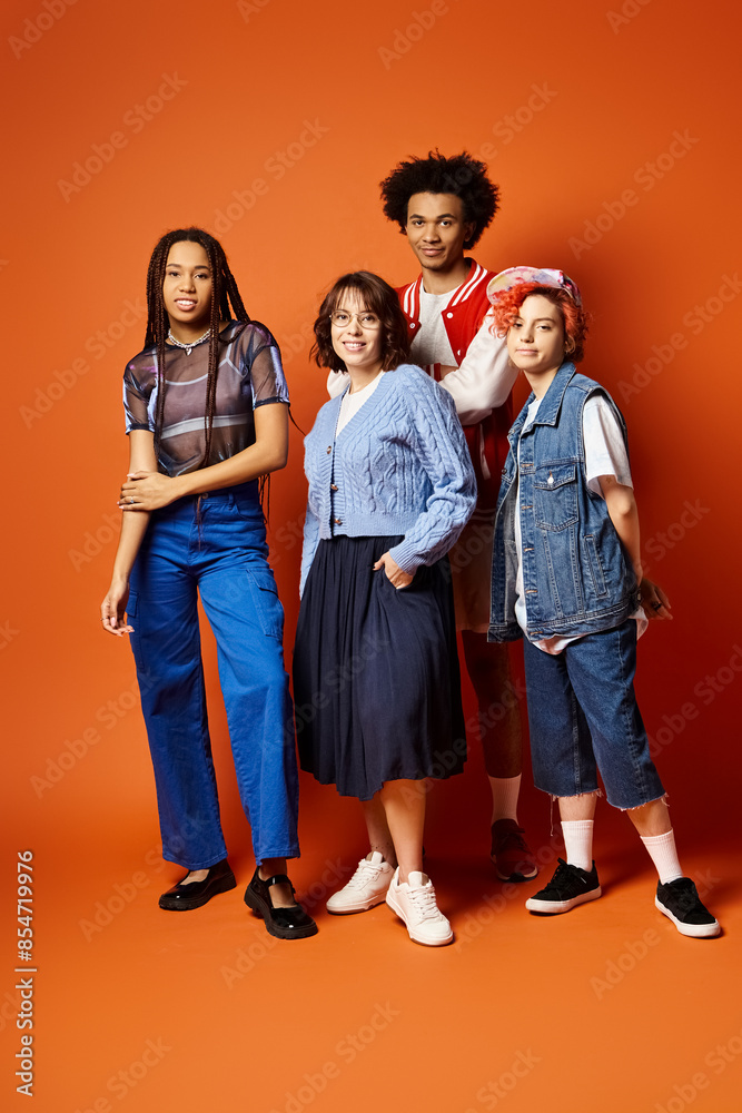Fototapeta premium A group of young multicultural friends, including a nonbinary person, standing together in stylish attire in a studio setting.