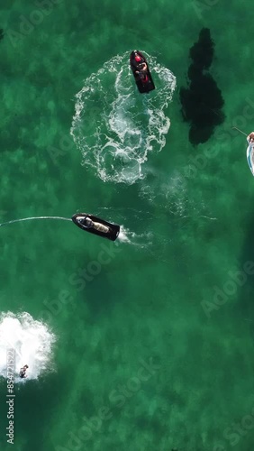 A man flies on a FlyBoard. Aerial top down view. Water extreme sport, azure summer sea with outdoors active people enjoying water sports. Flyboarding and seariding, Recreation and sports concepts. photo