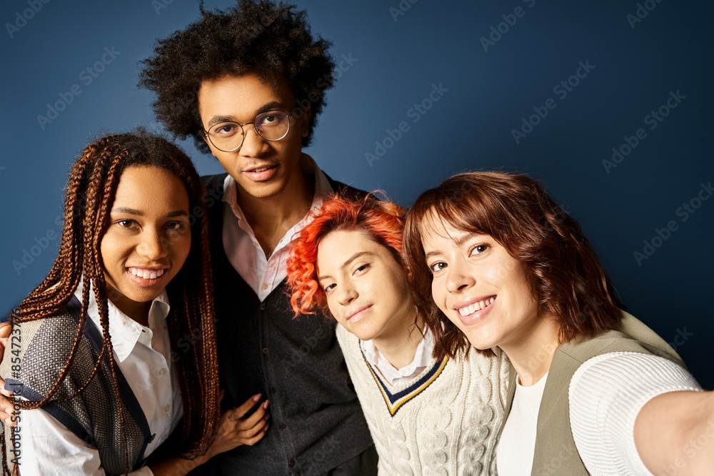 Fototapeta premium Young multicultural friends, including a nonbinary person, stand together in stylish attire, posing for a picture on a dark blue background.